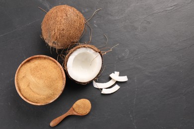 Photo of Spoon with coconut sugar, bowl and fruits on dark textured table, flat lay. Space for text