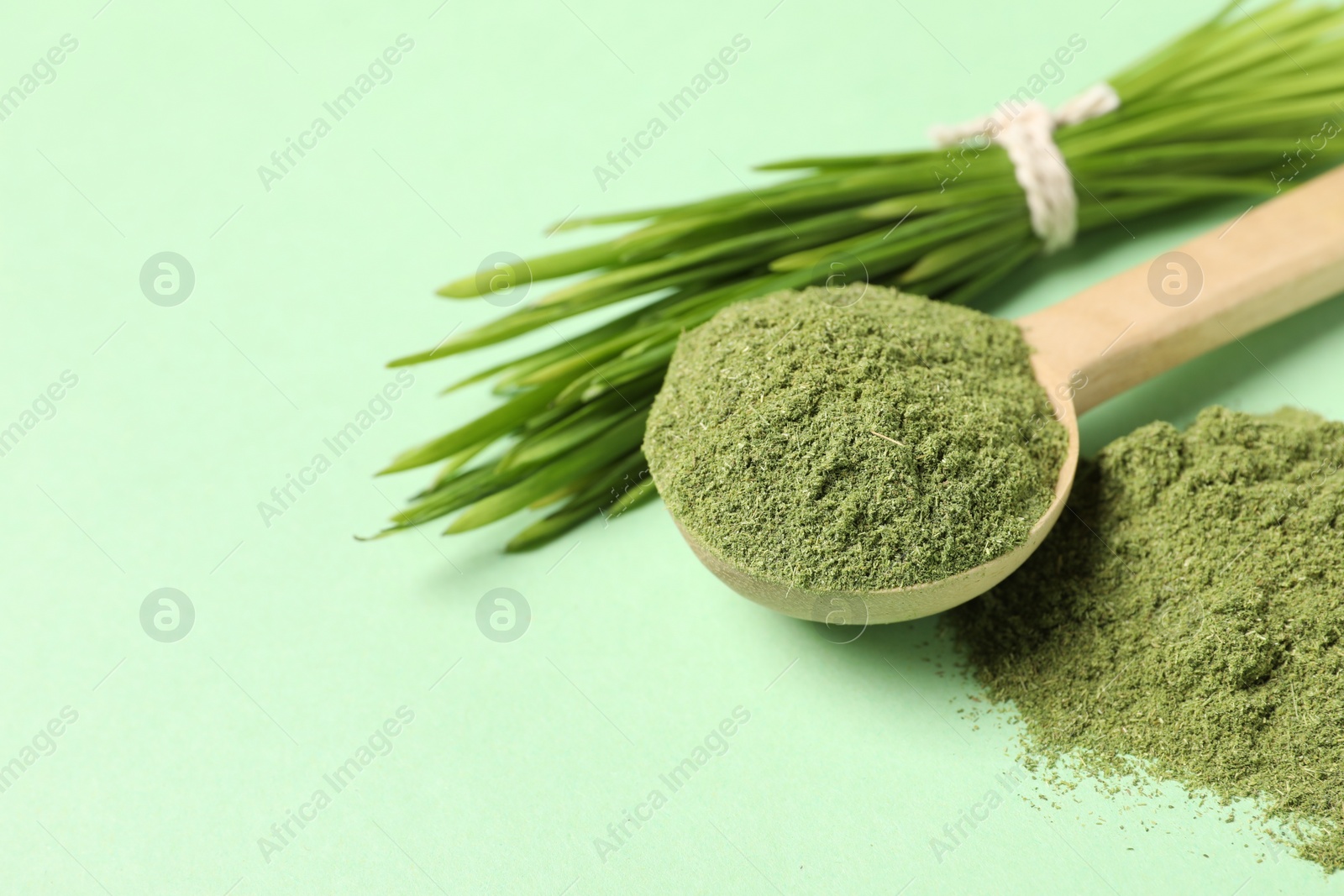 Photo of Wheat grass powder and fresh sprouts on green table, closeup. Space for text