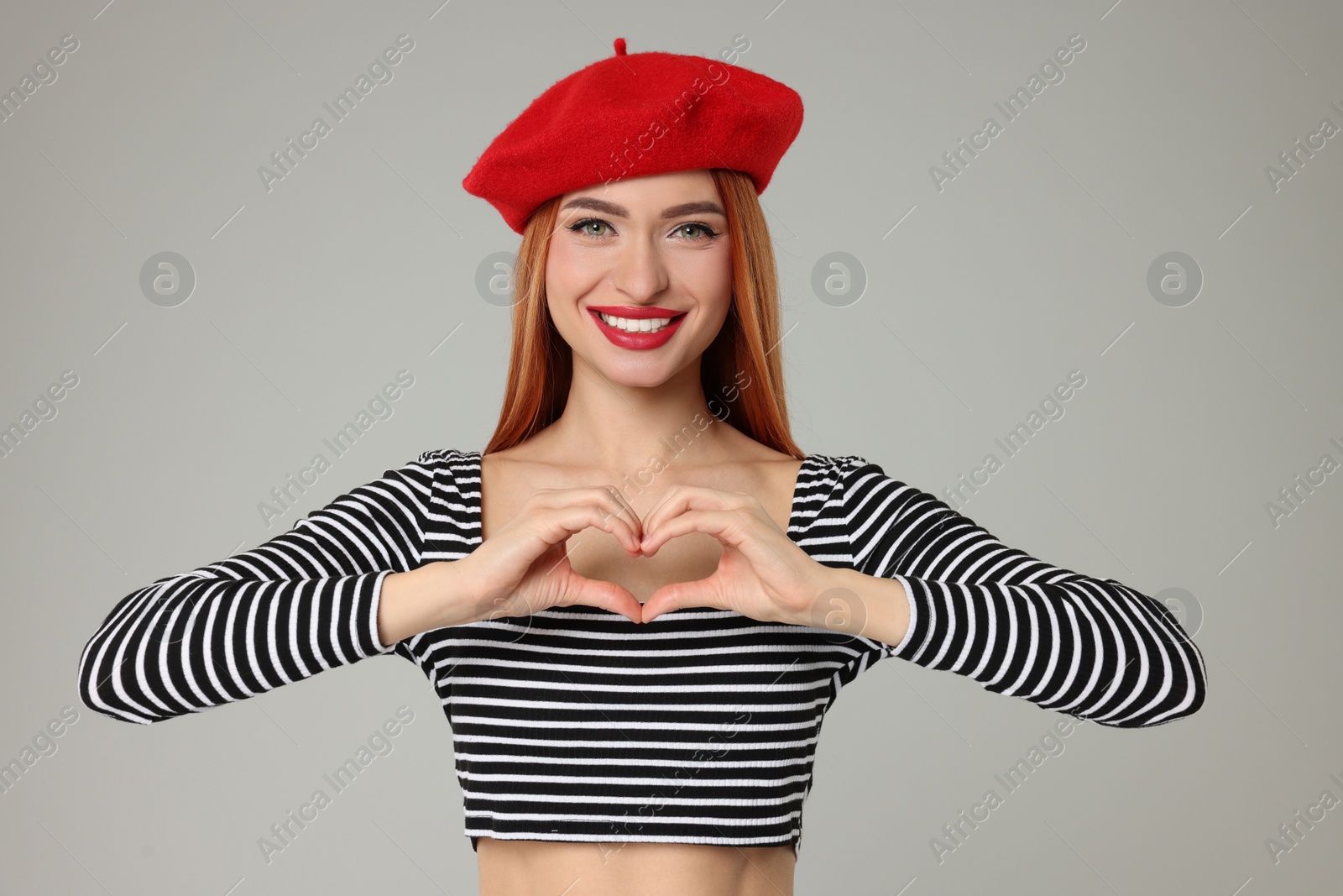 Photo of Young woman making heart with hands on light grey background