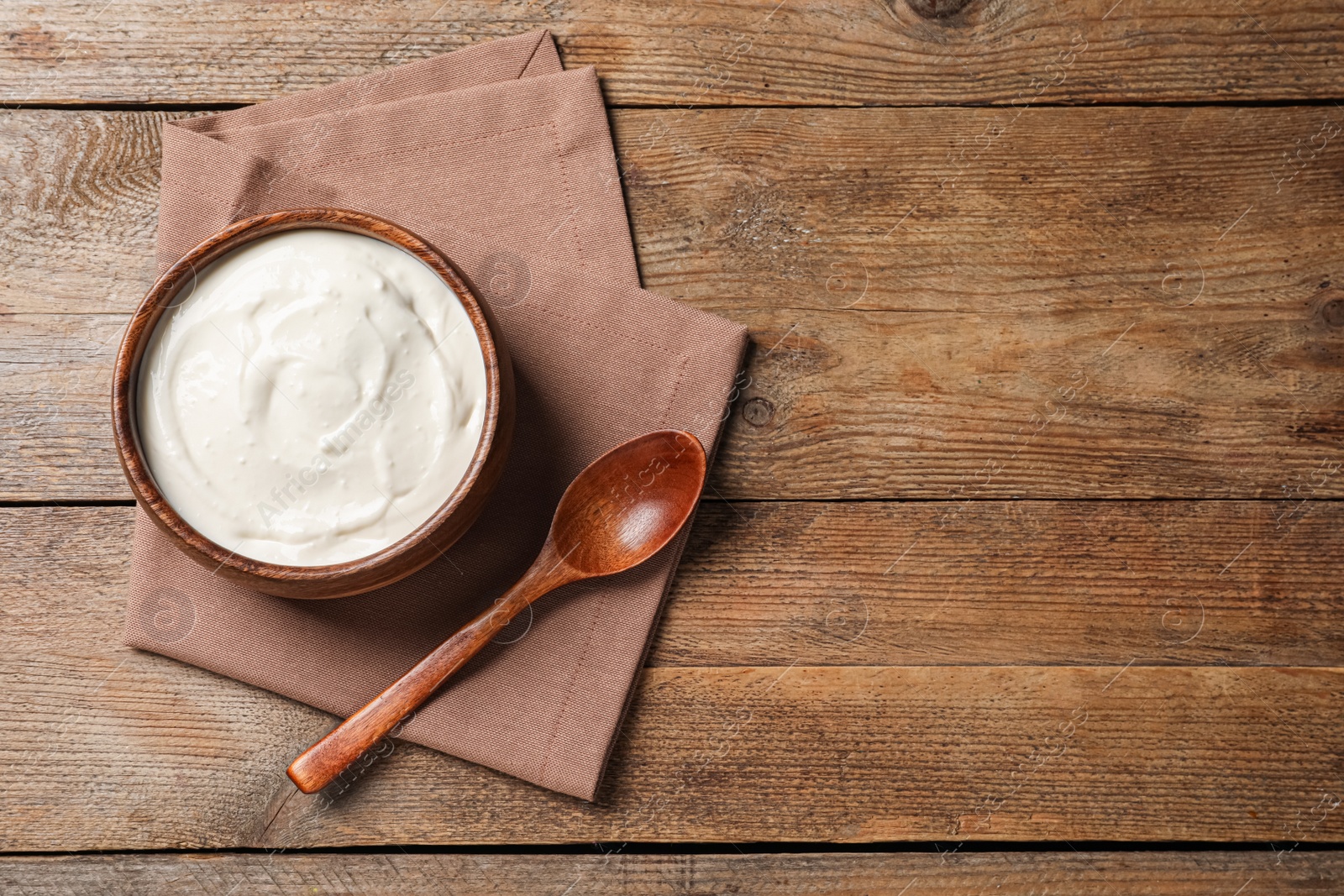 Photo of Bowl of tasty yogurt on wooden table, flat lay. Space for text