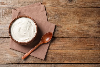 Photo of Bowl of tasty yogurt on wooden table, flat lay. Space for text