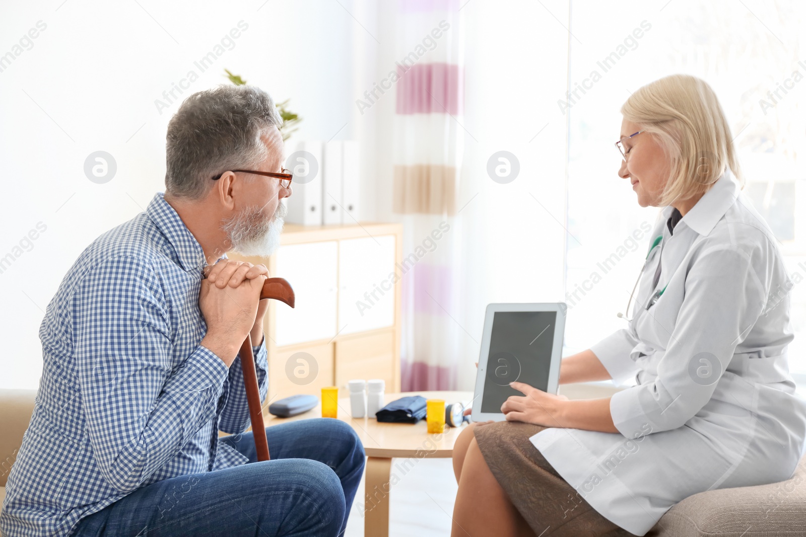 Photo of Mature doctor consulting patient at home