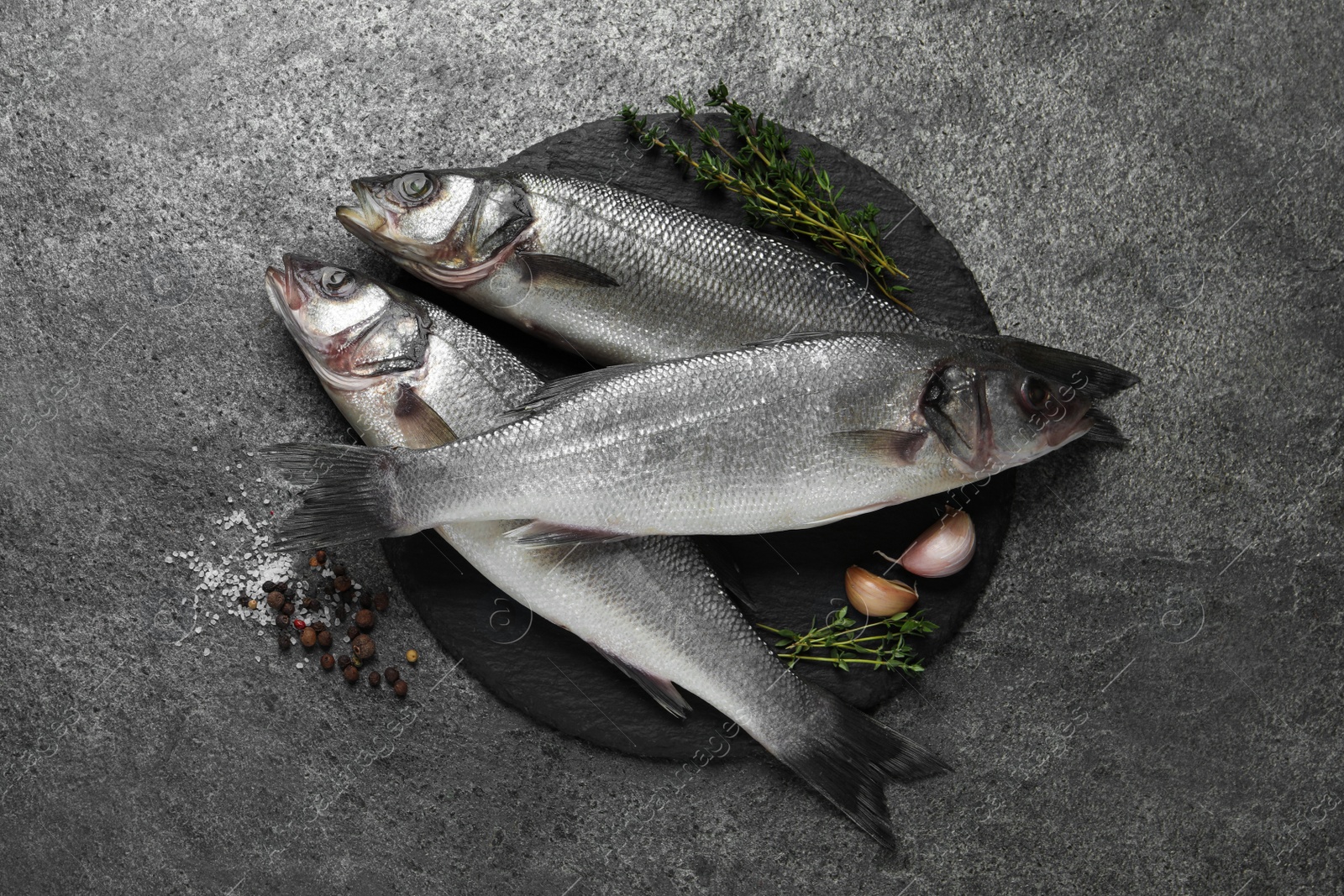 Photo of Tasty sea bass fish on grey textured table, flat lay
