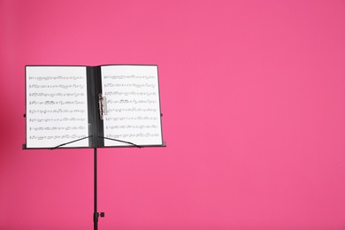 Photo of Note stand with music sheets on color background. Space for text
