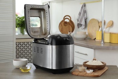 Photo of Breadmaker and products on wooden table in kitchen