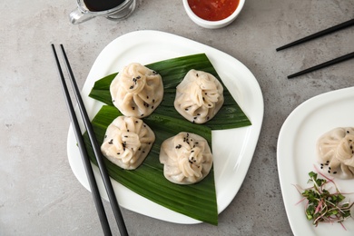 Photo of Plate with tasty baozi dumplings and chopsticks on grey table, top view