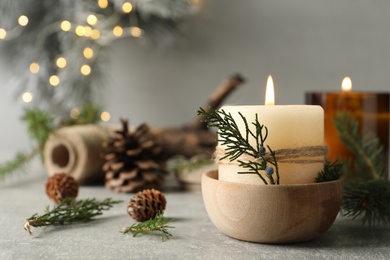 Photo of Burning candle with pinecone scent on light grey table, space for text