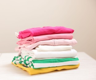 Photo of Stack of folded clothes on white table against grey background