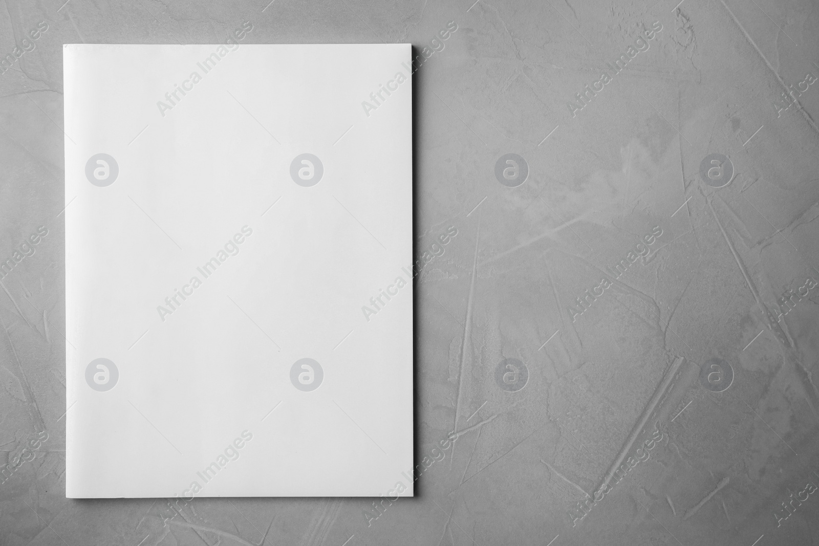 Photo of Blank book on light grey stone background, top view. Mock up for design