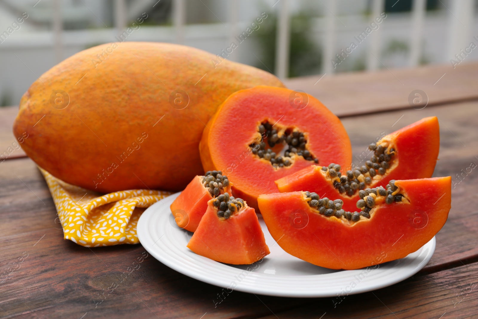 Photo of Ripe cut and whole papaya fruits on wooden table