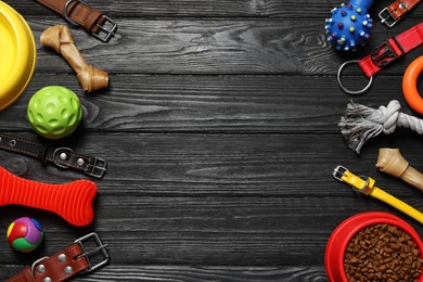 Different dog accessories, collars and food on black wooden background, flat lay. Space for text