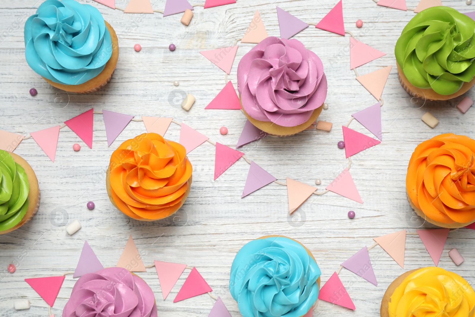 Photo of Colorful birthday cupcakes on white wooden table, flat lay