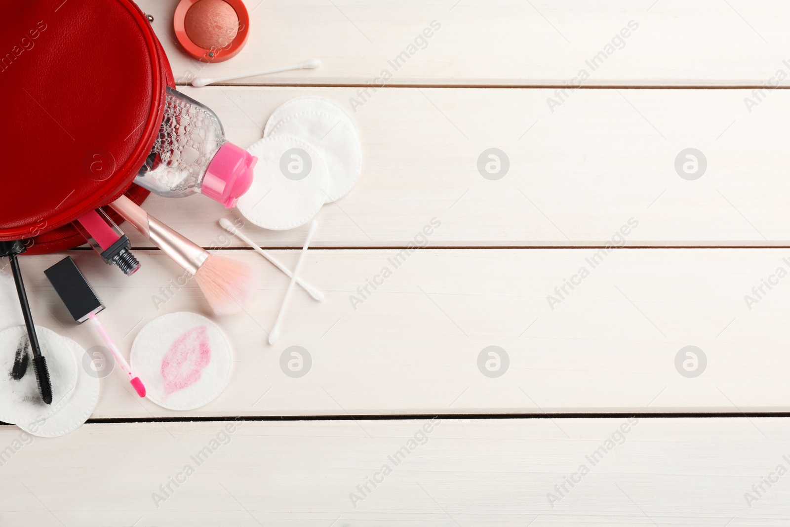 Photo of Dirty cotton pads, swabs, cosmetic products and micellar cleansing water on white wooden background, flat lay. Space for text