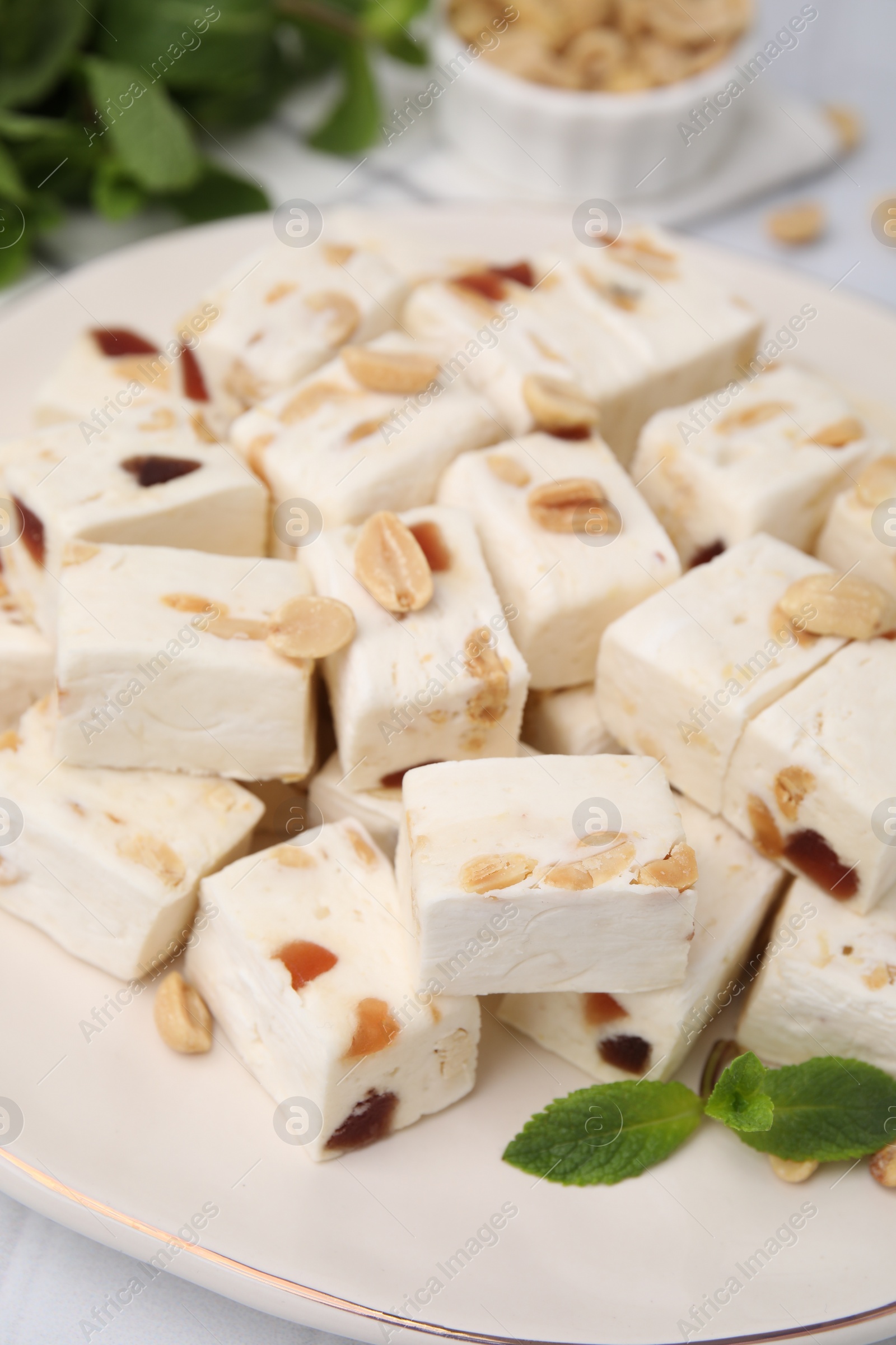 Photo of Pieces of delicious nutty nougat on plate, closeup