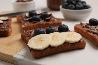 Different tasty toasts with nut butter and products on table, closeup