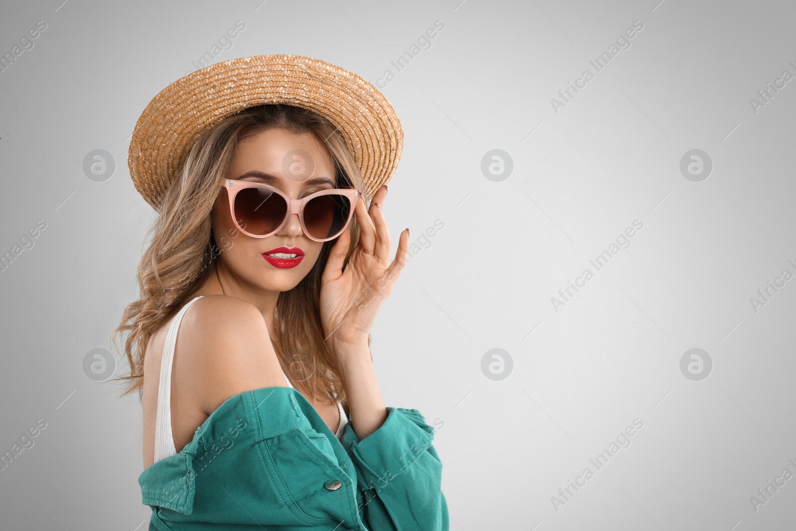 Photo of Young woman wearing stylish sunglasses and hat on light grey background. Space for text