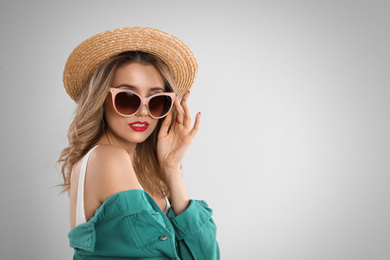 Photo of Young woman wearing stylish sunglasses and hat on light grey background. Space for text