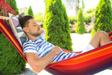 Photo of Man sleeping in hammock outdoors on warm summer day