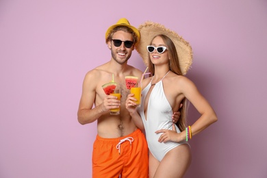 Photo of Young couple in beachwear with cocktails on color background