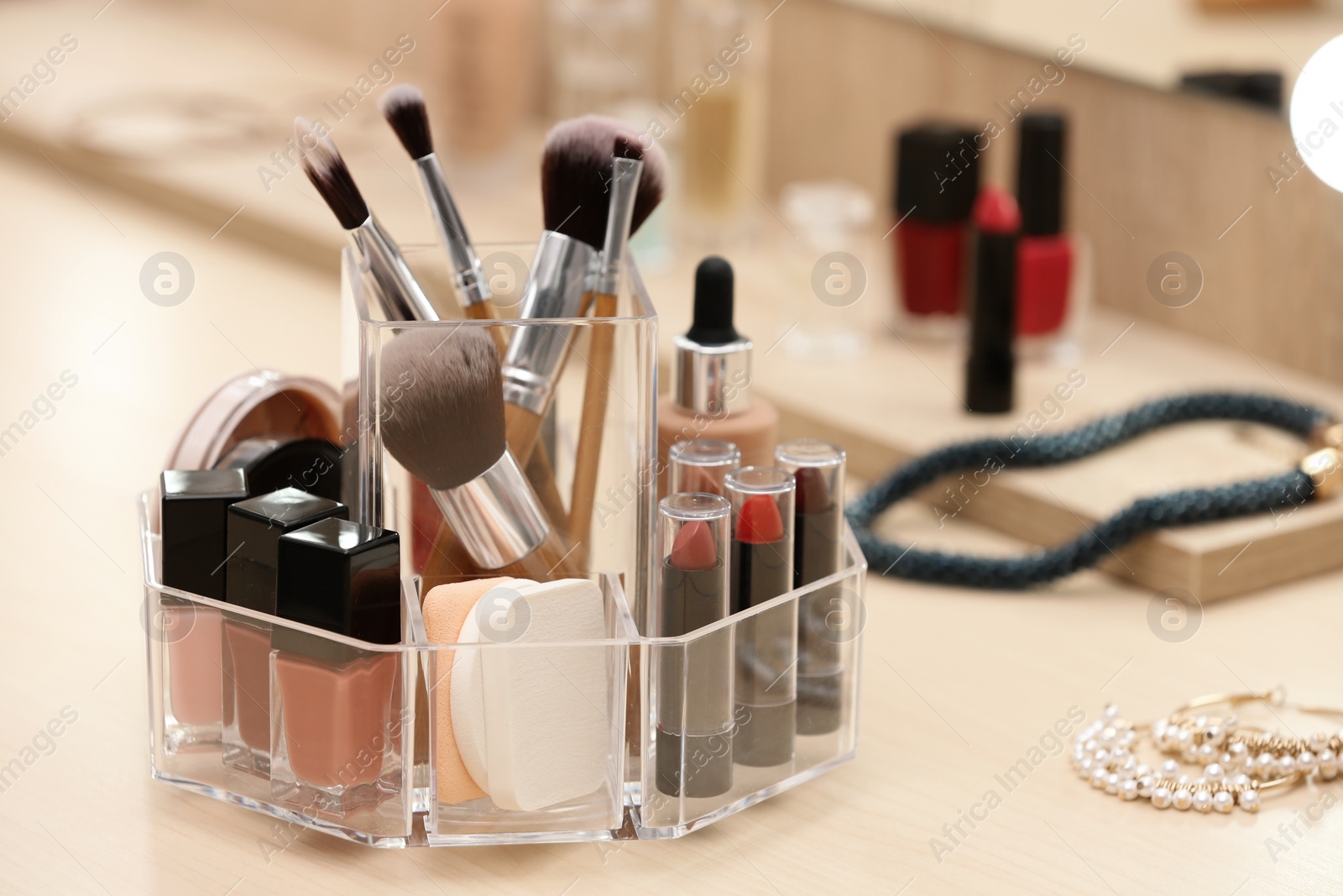 Photo of Organizer with cosmetic products and makeup accessories on dressing table