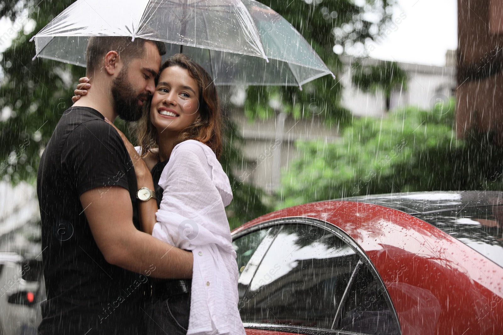 Photo of Young couple with umbrella enjoying time together under rain on city street, space for text