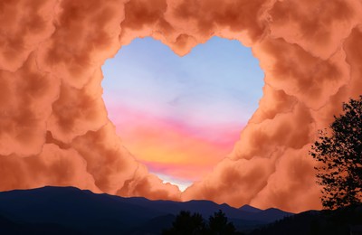 Image of Beautiful sunset sky, view through heart shaped gap formed from orange clouds in mountains