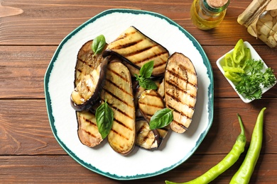 Photo of Plate with fried eggplant slices on wooden table, top view