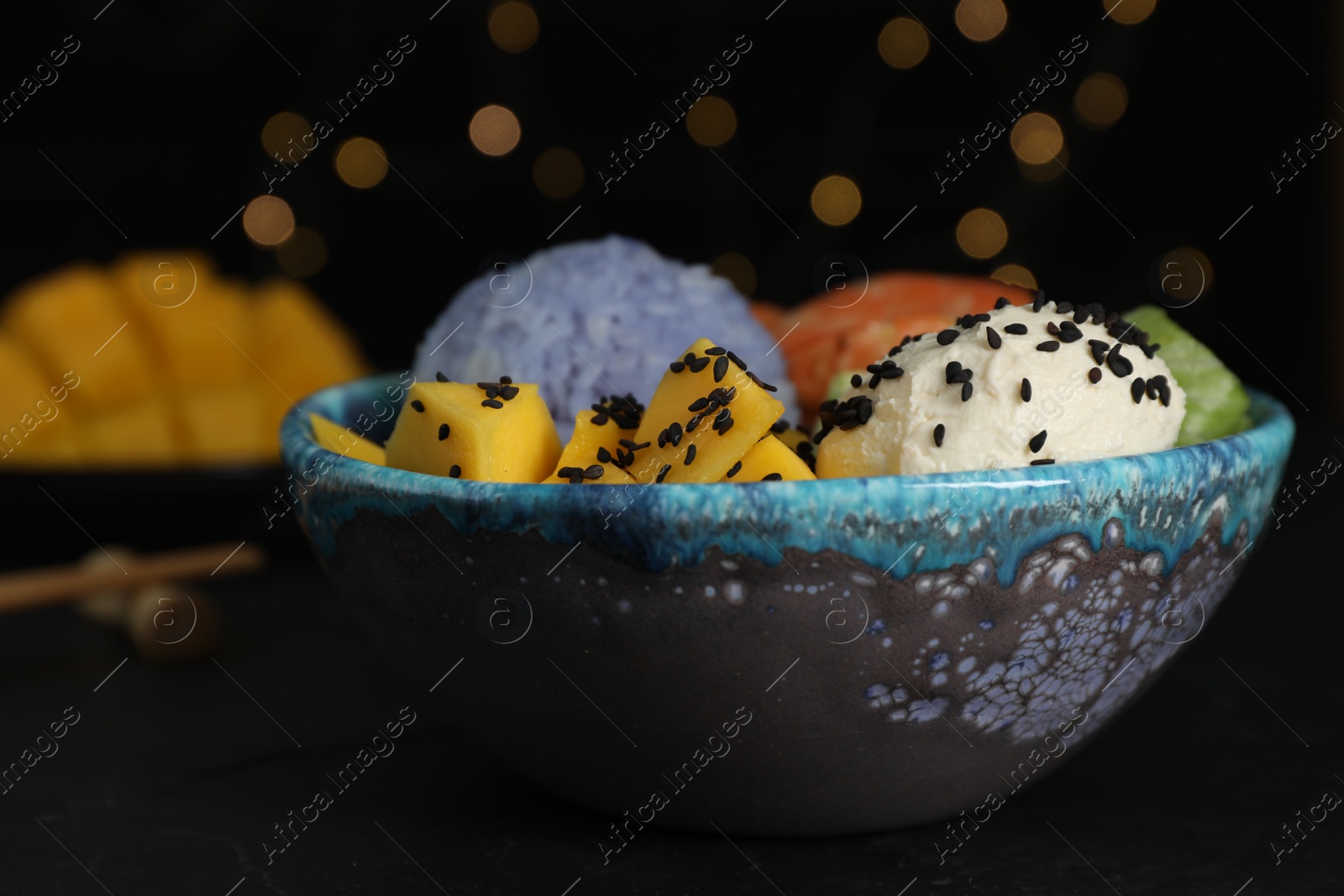 Photo of Delicious poke bowl on table against blurred lights, closeup