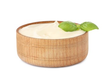 Photo of Mayonnaise with basil leaves in wooden bowl isolated on white