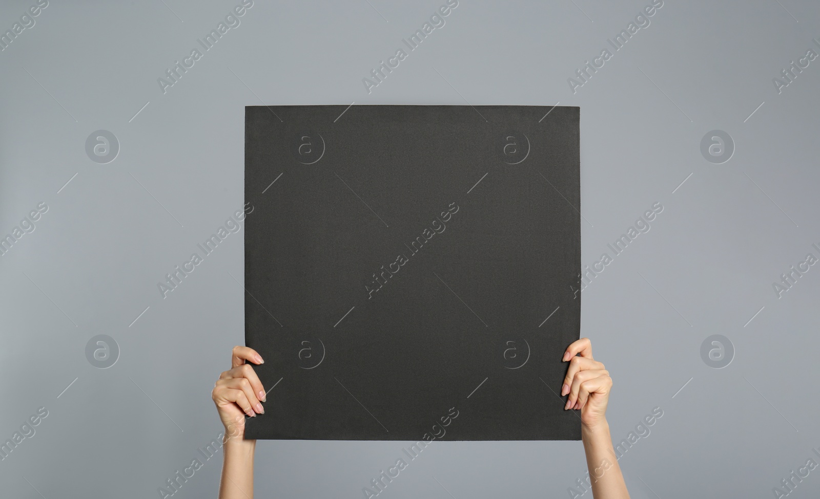 Photo of Woman holding black blank poster on grey background, closeup. Mockup for design