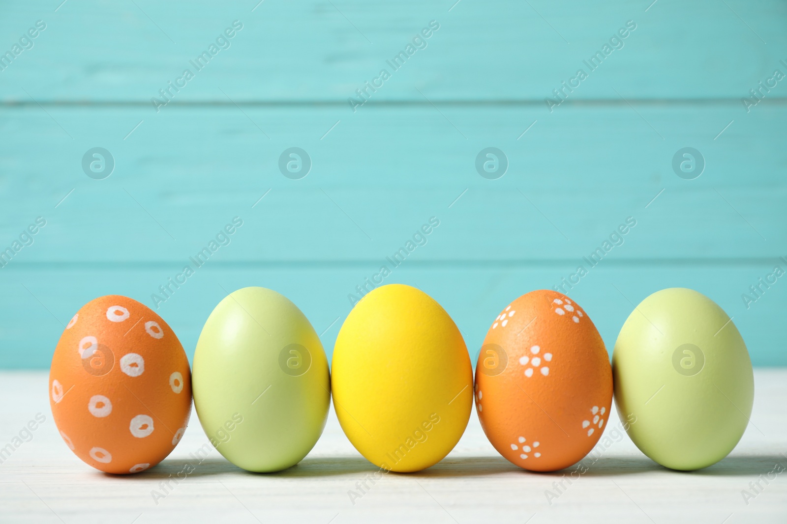 Photo of Colorful Easter eggs on white wooden table. Space for text