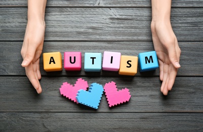 Woman with color cubes on wooden background. Autism concept