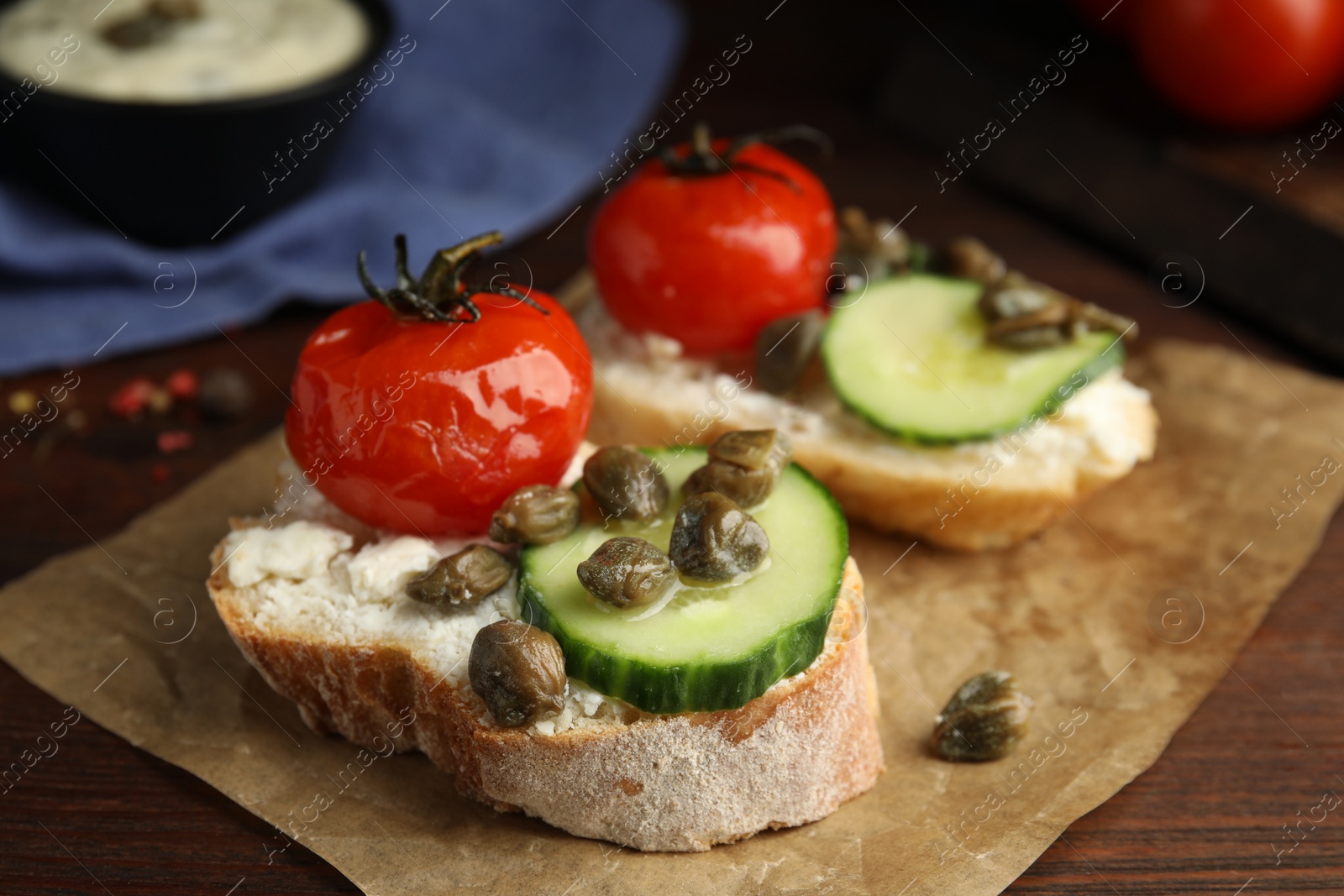 Photo of Tasty bruschettas with vegetables and capers on wooden table, closeup