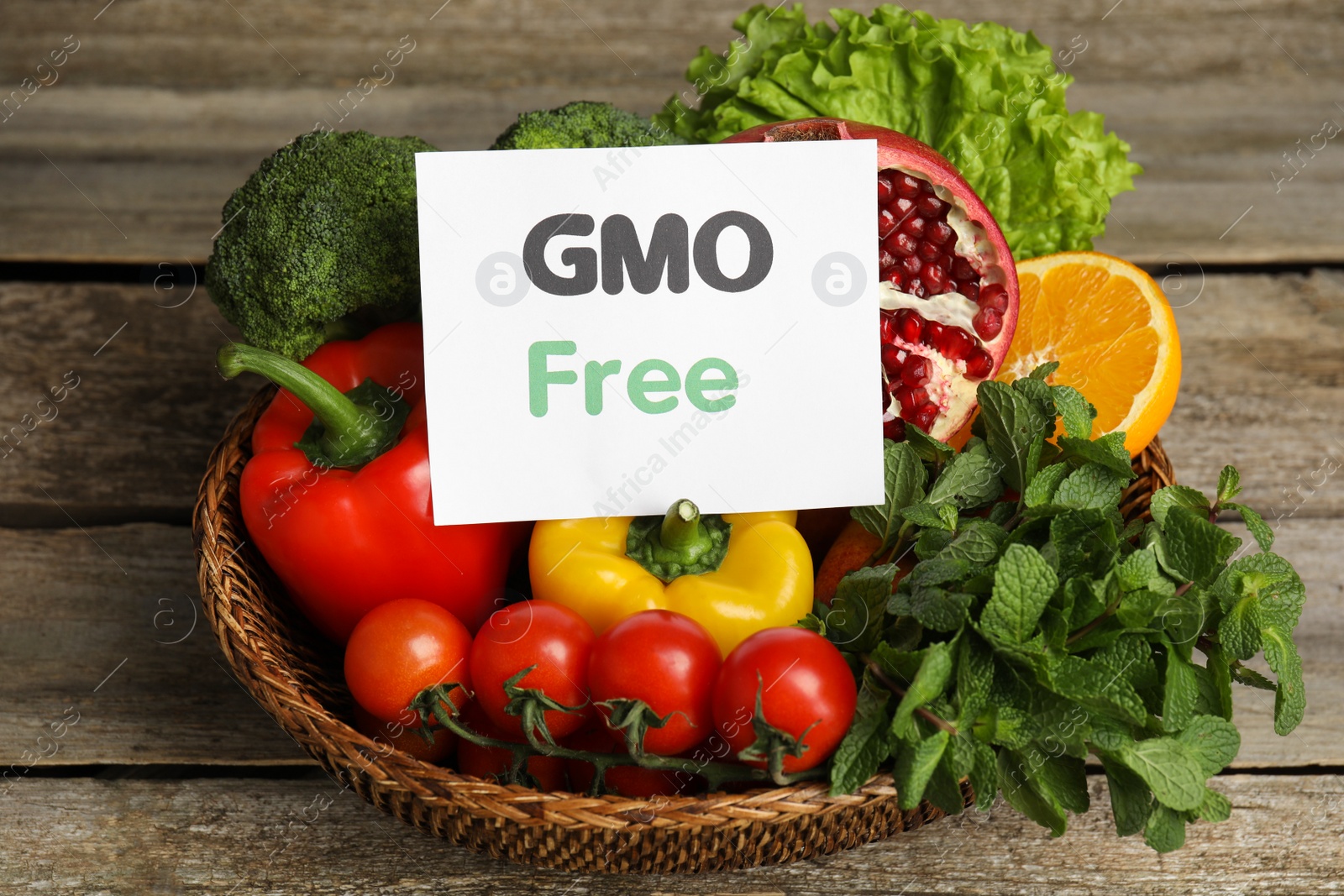 Photo of Tasty fresh GMO free products and paper card on wooden table