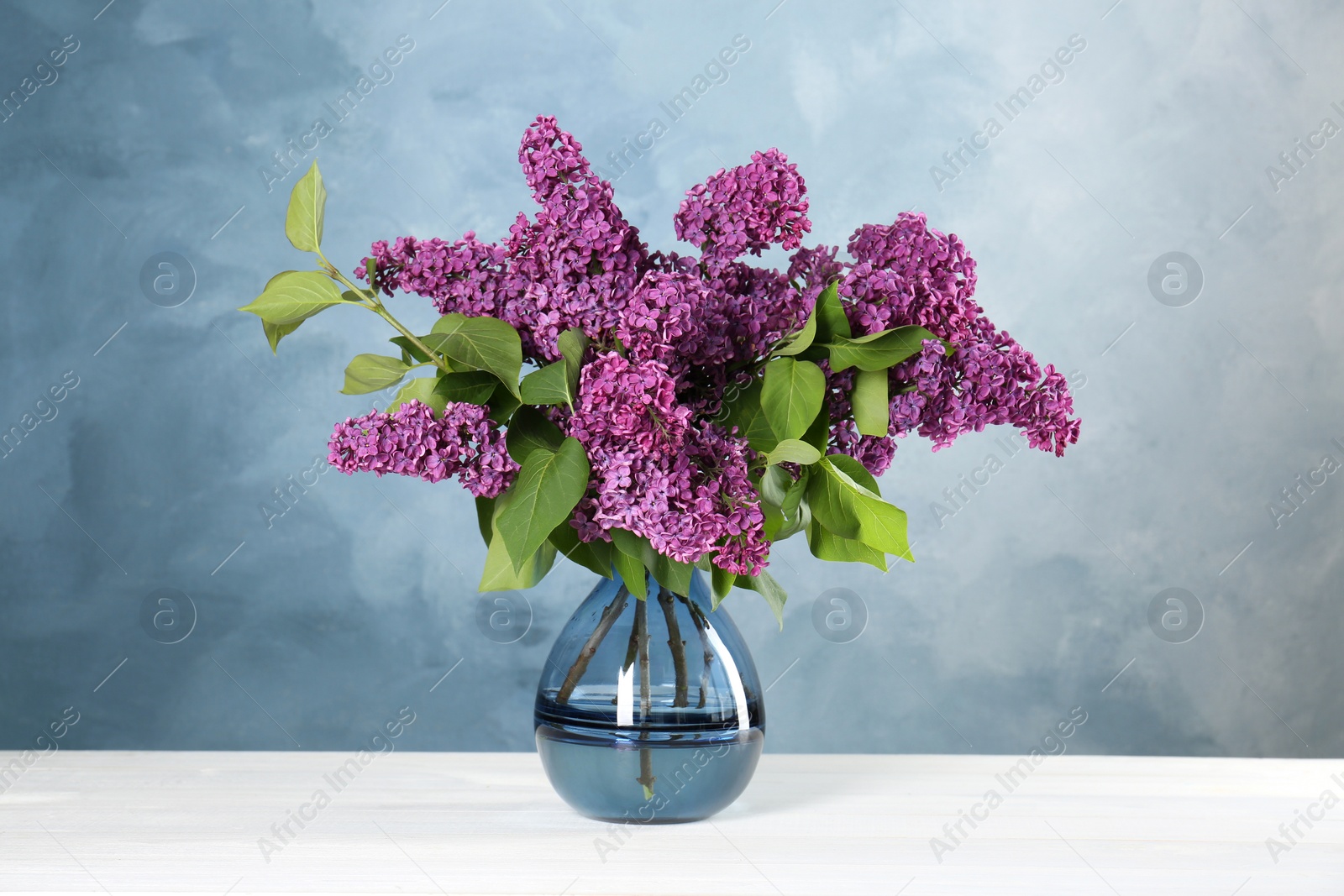 Photo of Beautiful lilac flowers in vase on white table