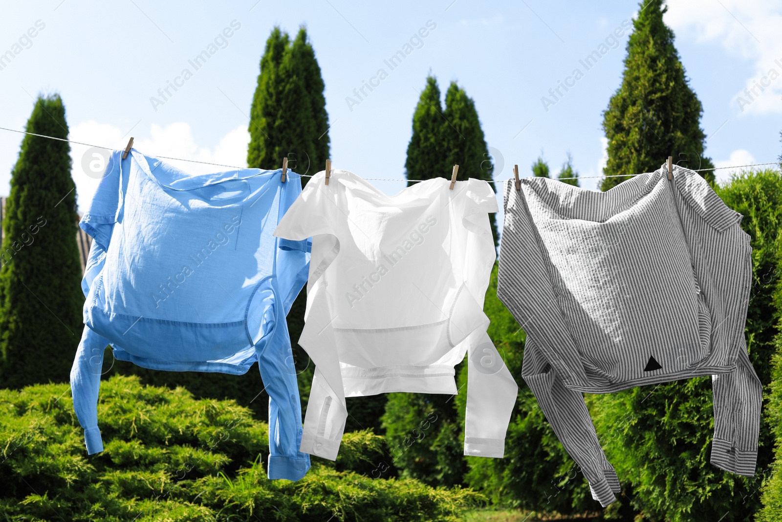 Photo of Clean clothes hanging on washing line in garden. Drying laundry