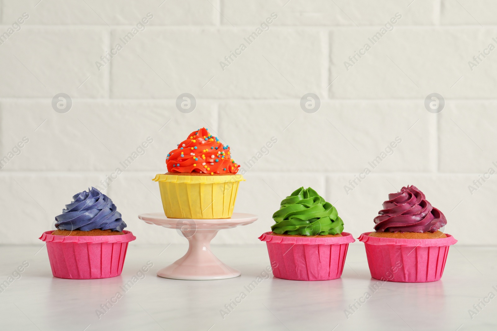 Photo of Delicious cupcakes with colorful cream on white table