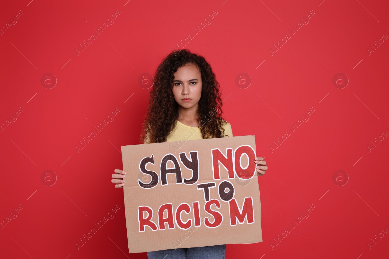Photo of African American woman holding sign with phrase Say No To Racism on red background