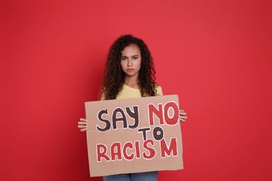 Photo of African American woman holding sign with phrase Say No To Racism on red background