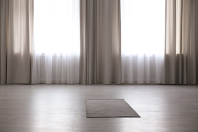Photo of Grey yoga mat on floor in spacious room