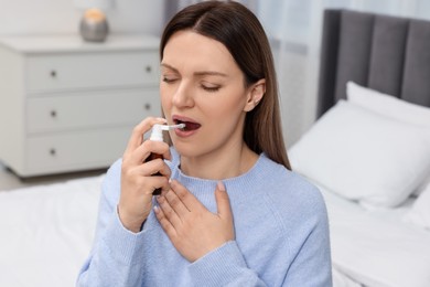 Photo of Adult woman using throat spray in bedroom