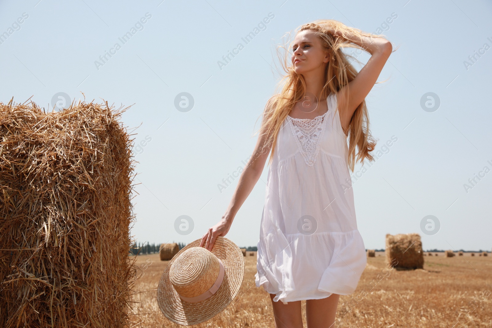 Photo of Beautiful young woman with straw hat near rolled hay bale on sunny day