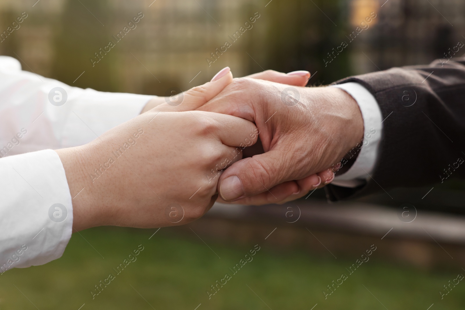 Photo of Trust and deal. Partners joining hands outdoors, closeup