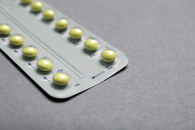 Photo of Birth control pills on grey background, closeup. Space for text