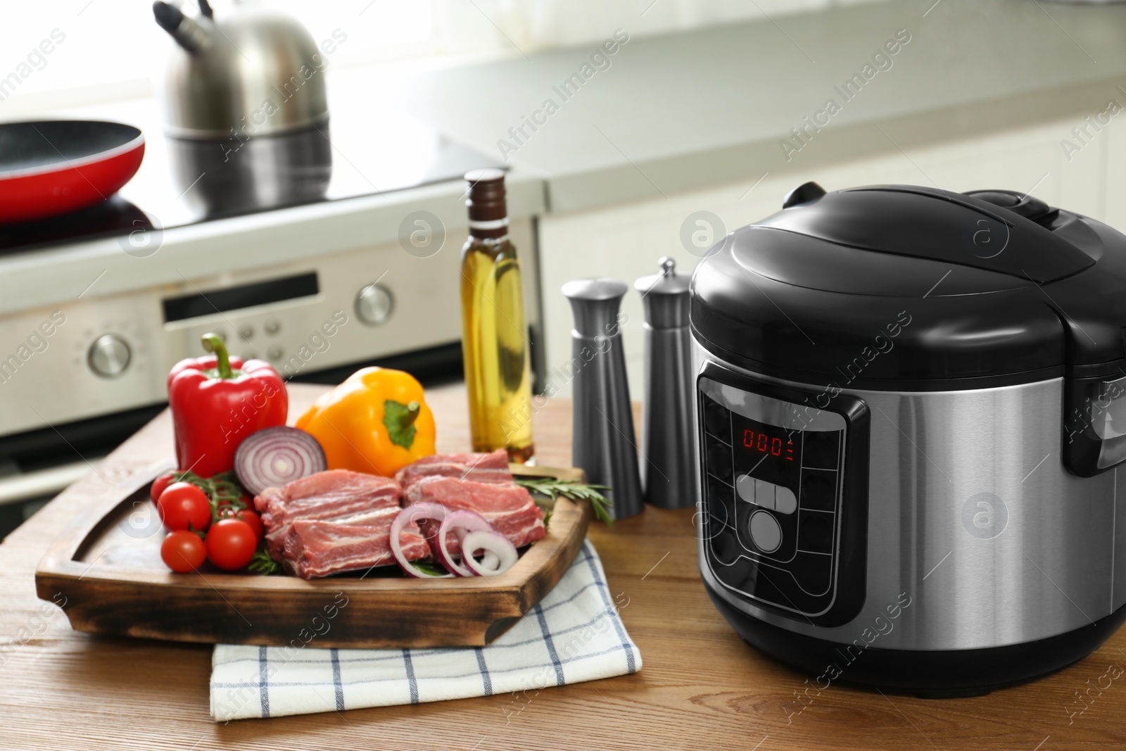 Photo of Modern multi cooker and products on wooden table in kitchen