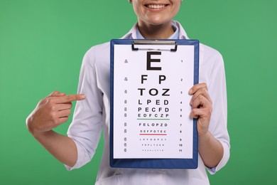 Ophthalmologist pointing at vision test chart on green background, closeup