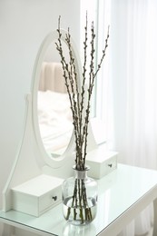 Photo of Beautiful blooming pussy willow branches on white dressing table indoors