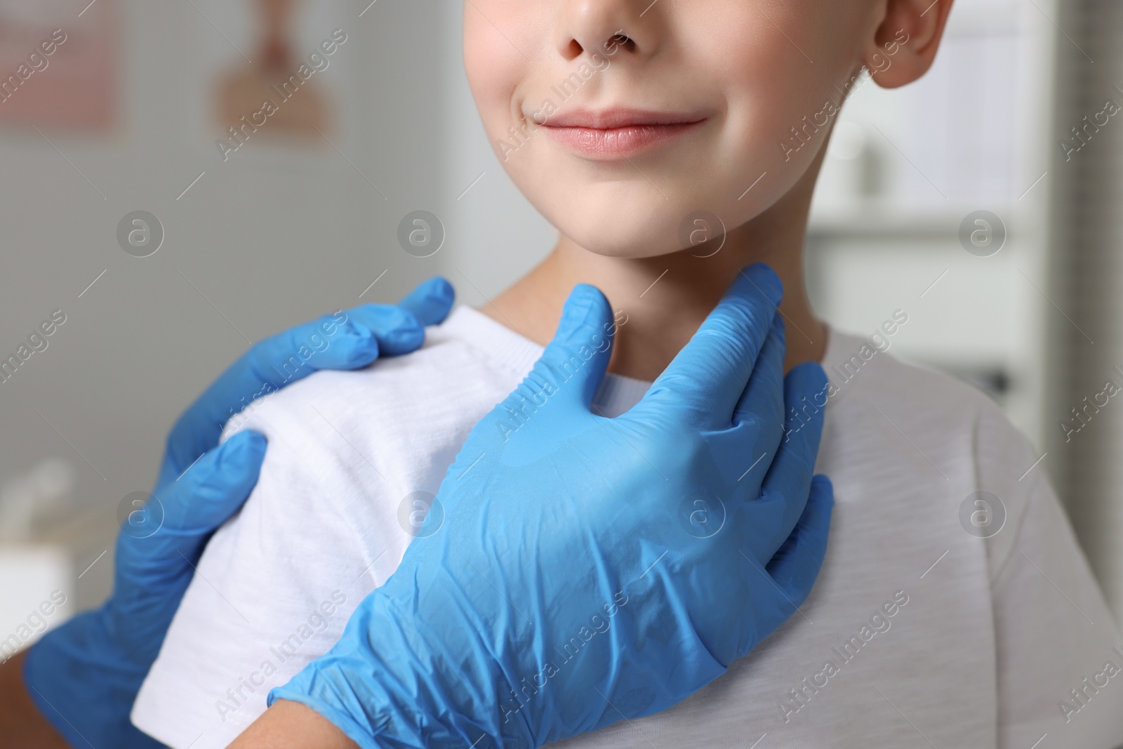 Photo of Endocrinologist examining boy's thyroid gland indoors, closeup