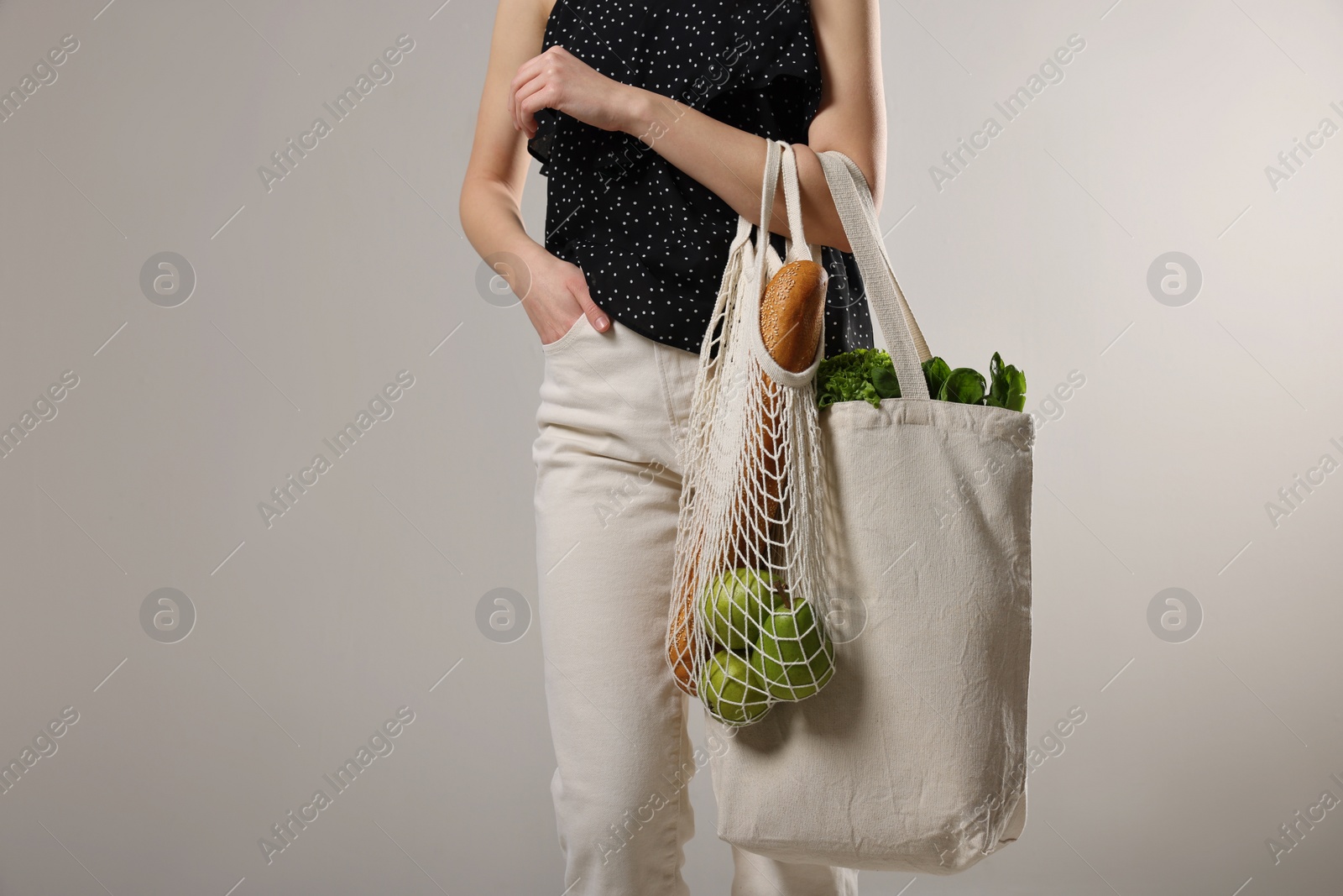 Photo of Woman with eco bags full of products on light background, closeup