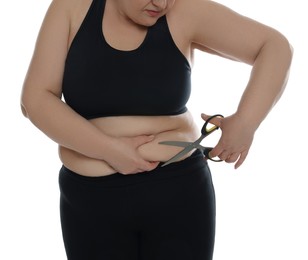 Photo of Obese woman with scissors on white background, closeup. Weight loss surgery